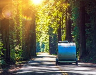 Rear view of a trailer being towed by a vehicle down a tree lined road